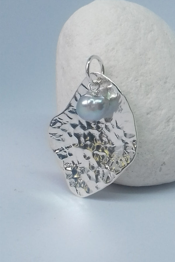 Silver pendant with a pearl on a stone surface