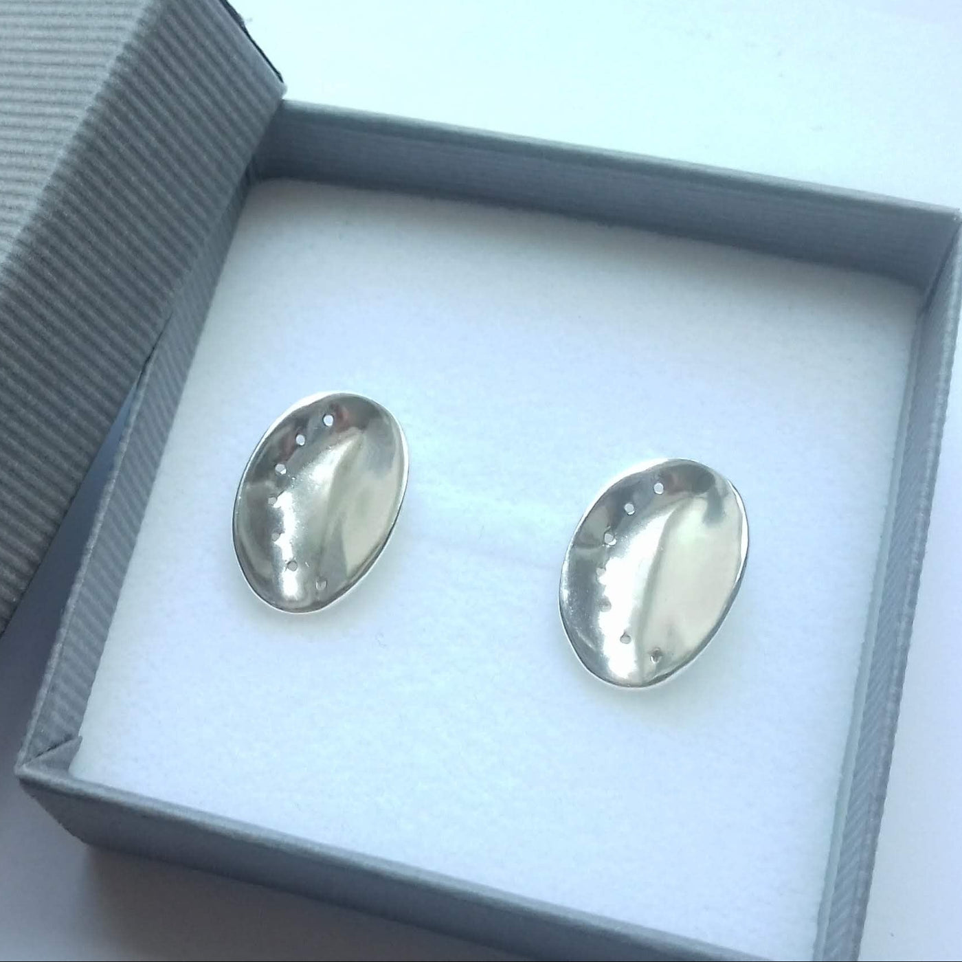 Silver ormer earrings in a 'Qwerky Guernsey' branded box on a white background