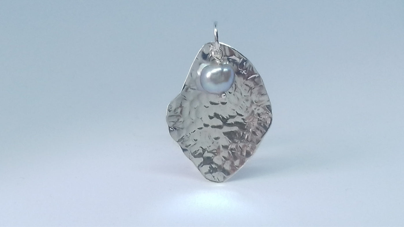 Silver potato peel textured pendant with a grey pearl on a light gray background