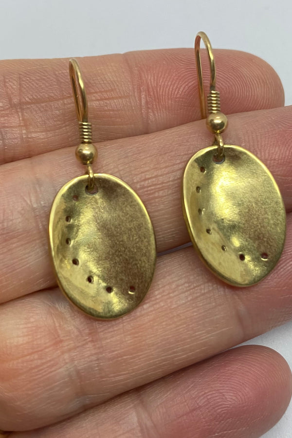 Guernsey ormer shell earrings in 9ct yellow gold, held in a hand. 