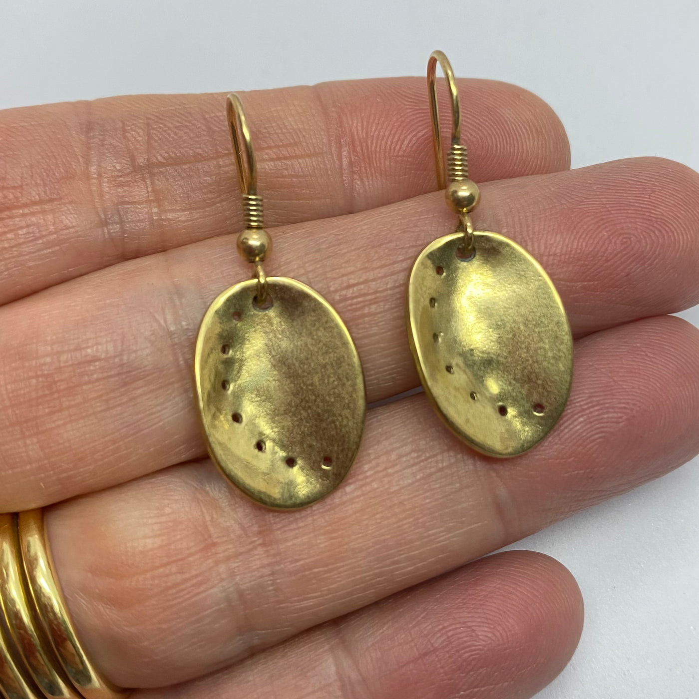 Guernsey ormer shell earrings in 9ct yellow gold, held in a hand. 