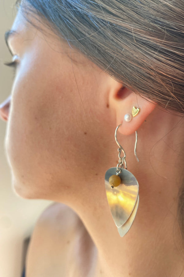 Close-up of a model wearing a silver and recycled plastic layered earring in muted yellows and oranges 