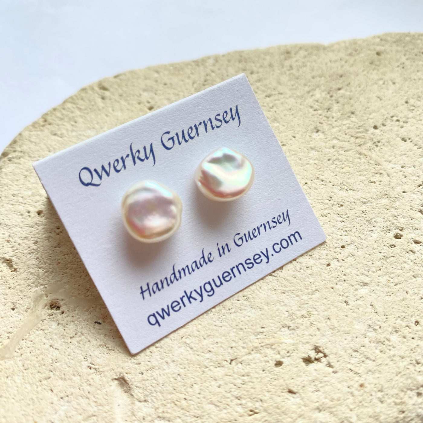 Pearl stud earrings on a Qwerky Guernsey branded card against a textured beige background