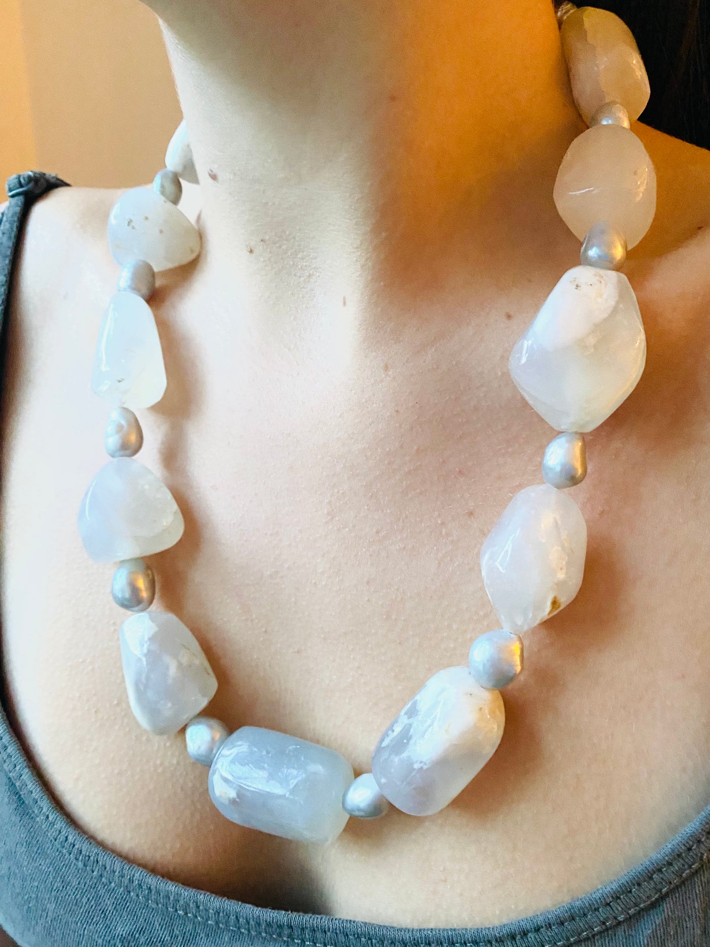 White opal necklace with large white beads and silver grey freshwater pearls worn on a model 