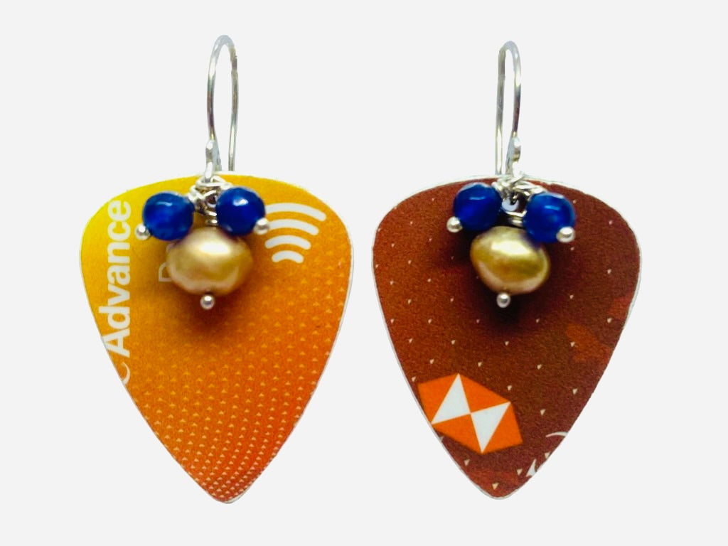 Tangerine Dream guitar pick earrings in bright oranges, with blue sapphire gemstone and freshwater pearl accents, on a white background. 