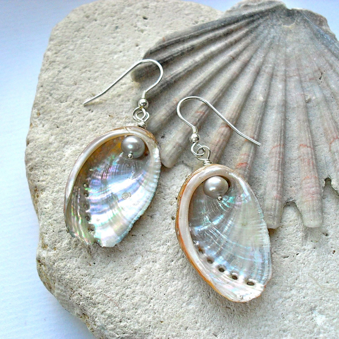 Guernsey Ormer Shell earrings with pearls on a stone surface