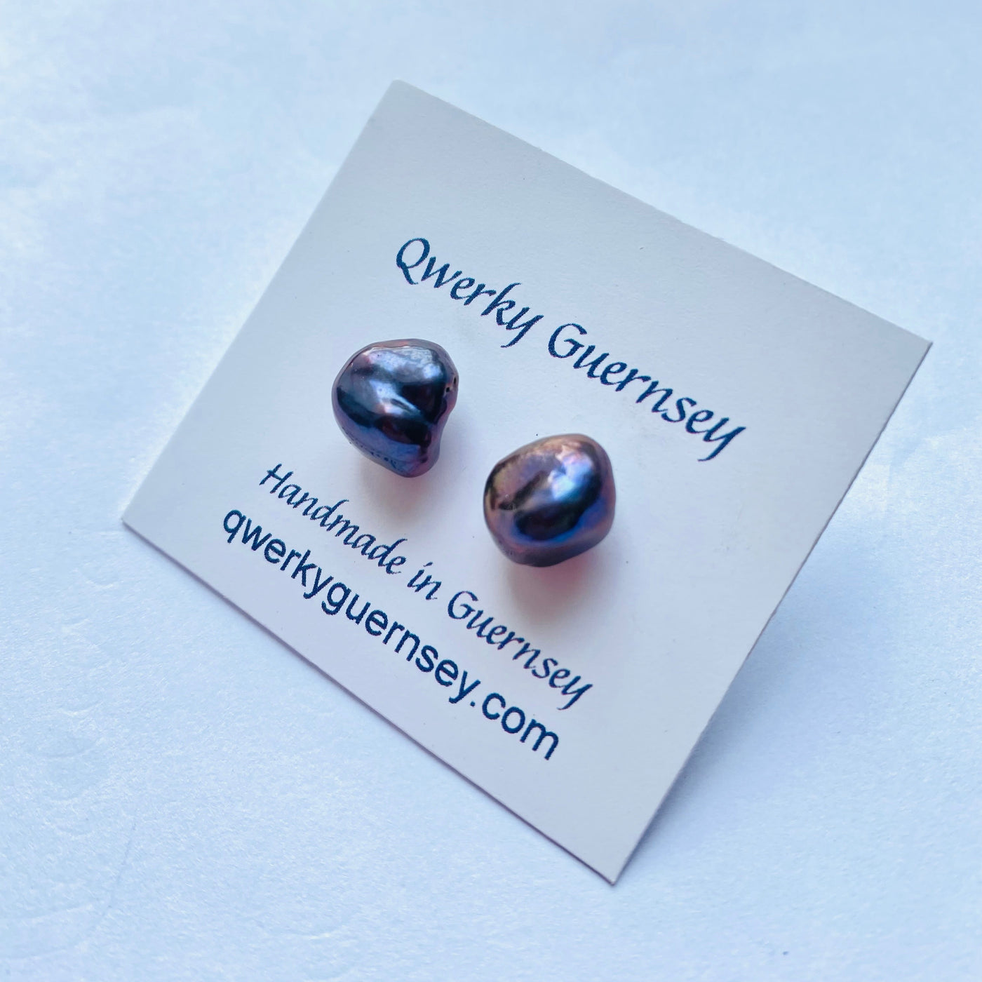 Pair of baroque pearl earrings on a Qwerky Guernsey branded card against a light blue background

