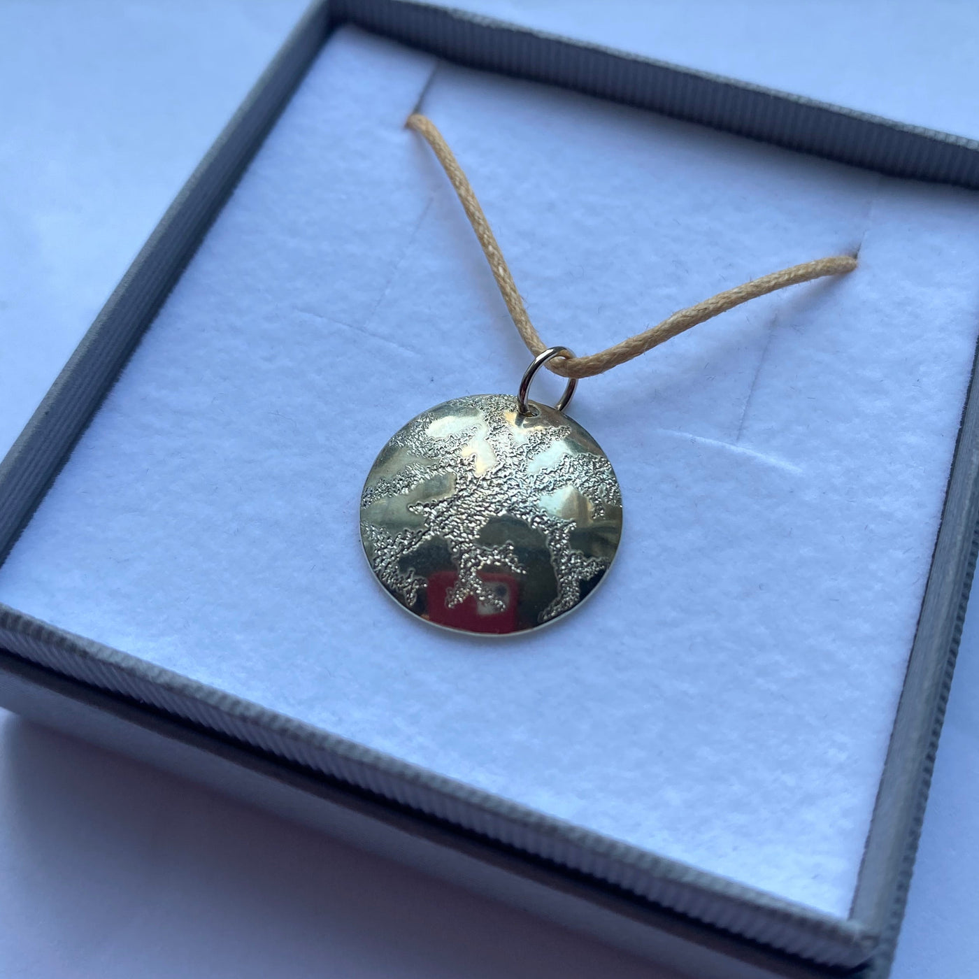 Hand engraved silver pendant displayed in a box