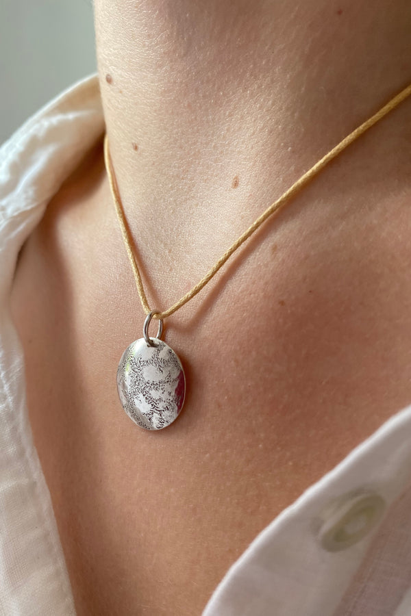 Hand engraved artisan necklace worn by a model in a white blouse