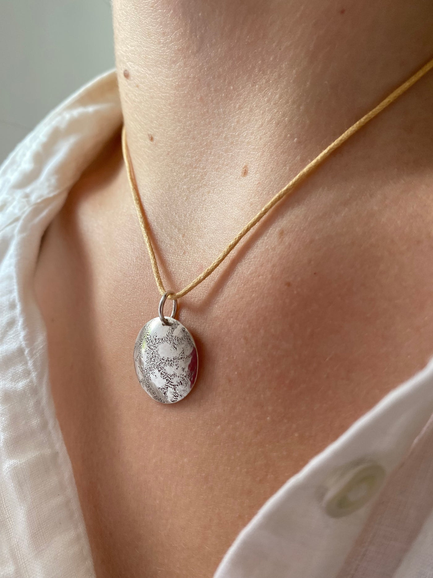 Hand engraved artisan necklace worn by a model in a white blouse