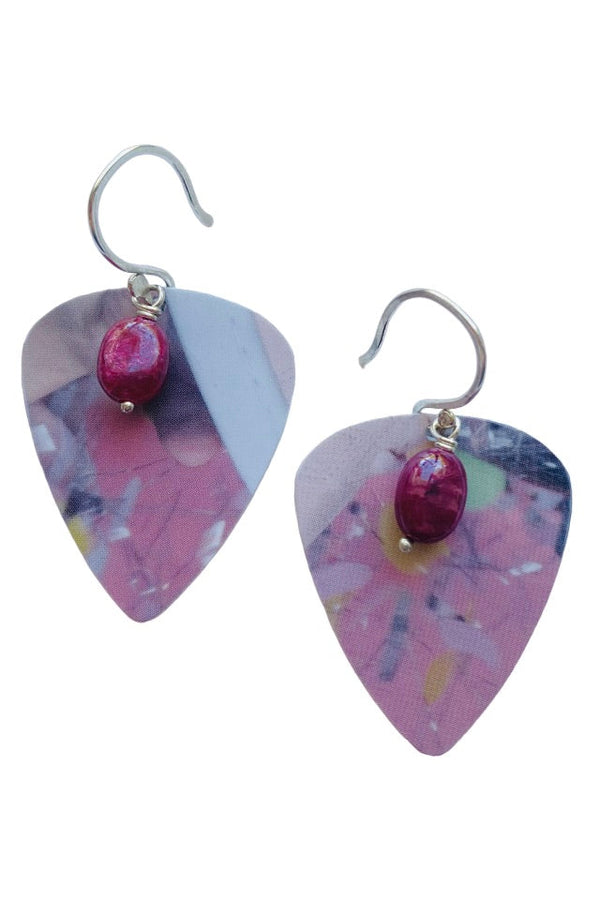 Pair of pink guitar pick earrings with red ruby gemstones on a white background