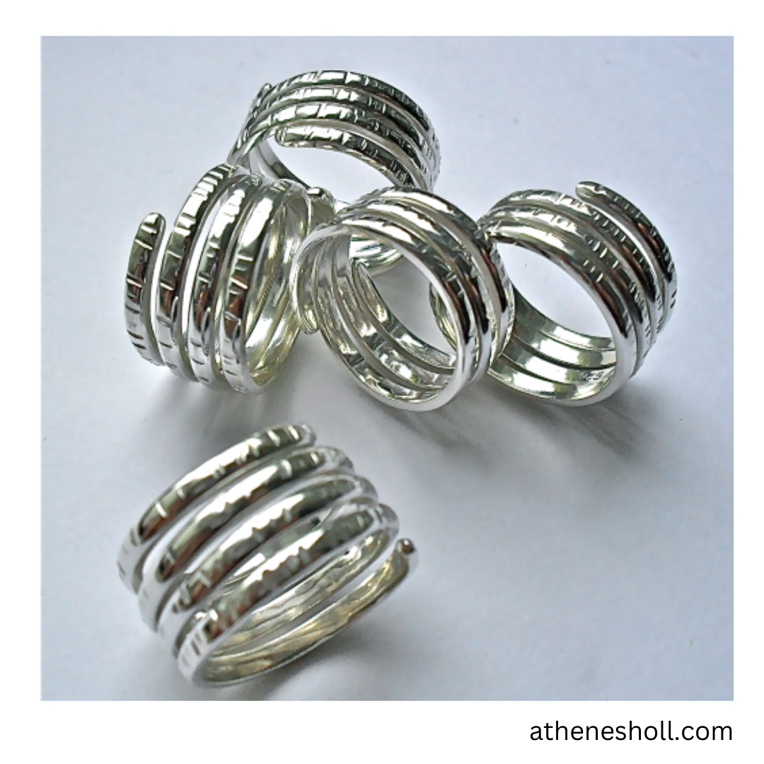 Five silver spiral wrap rings with textured ridges, displayed on a light gray background with a website watermark in the bottom right corner.