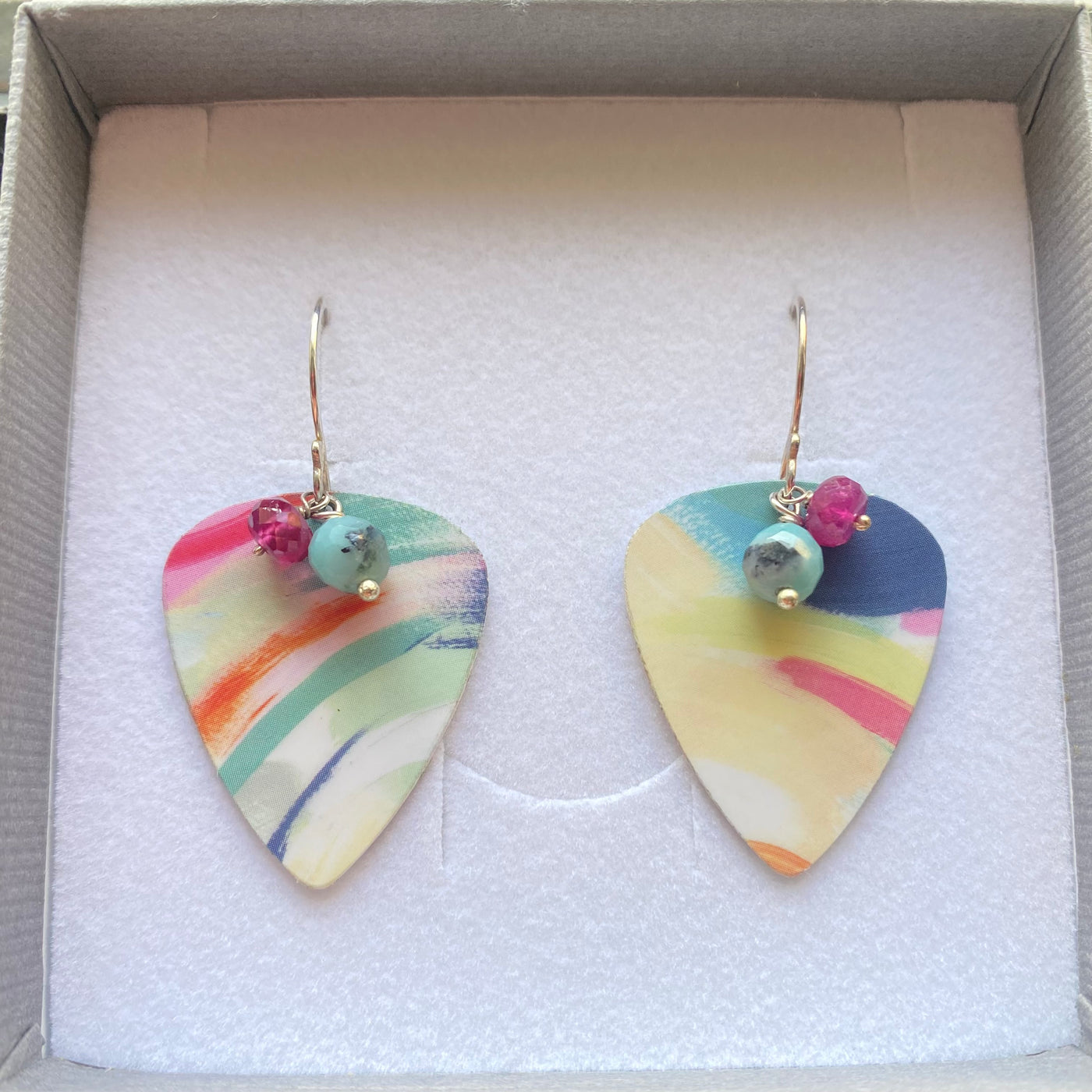 Colorful guitar pick-shaped earrings with rubies and amazonite gemstones in a box