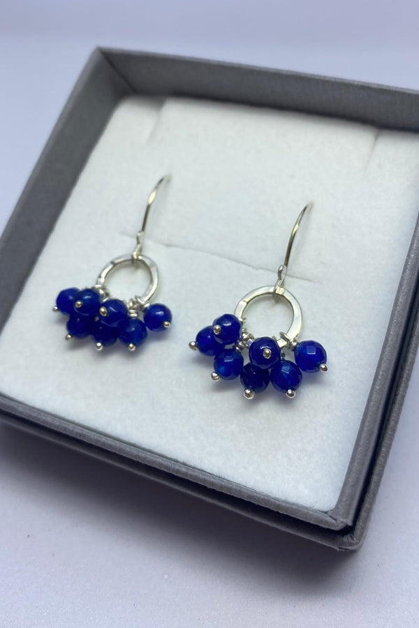 Pair of blue beaded earrings in a gray box on a white background