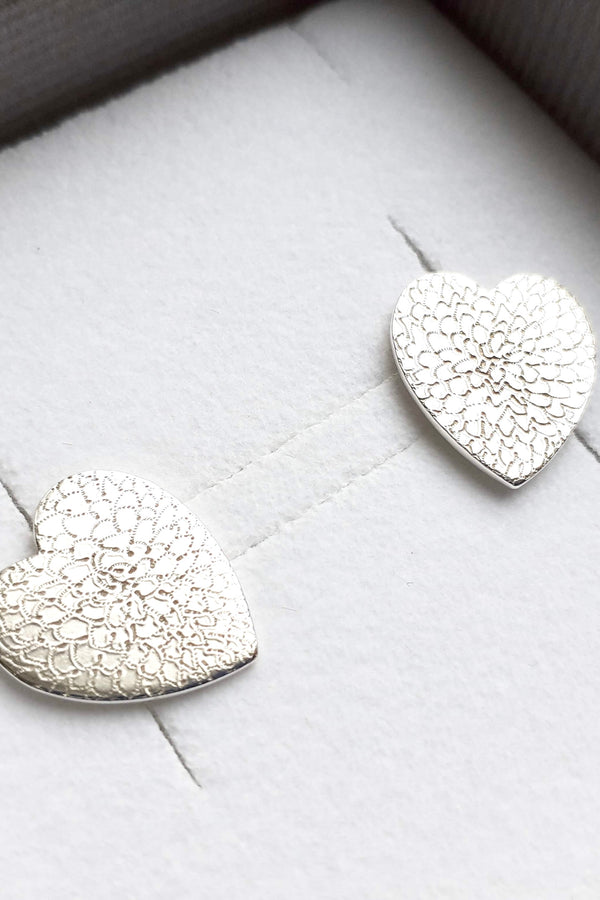 Heart-shaped silver earrings in a box