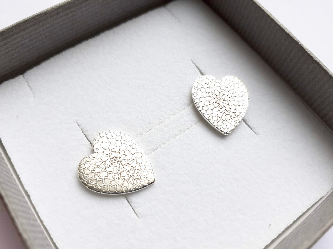 Heart-shaped silver earrings in a box