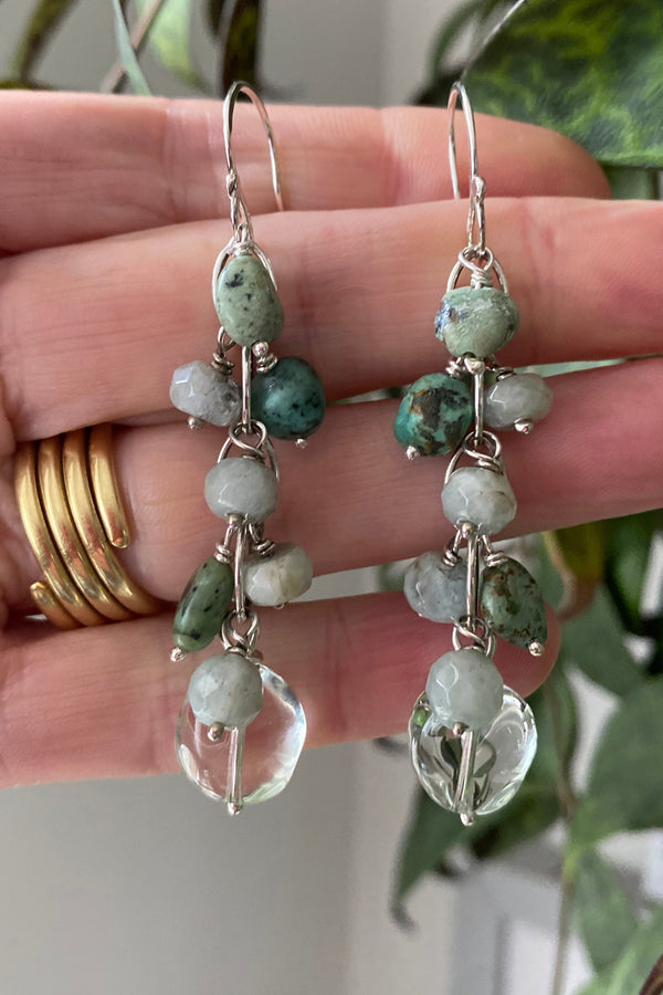 Waterfall style earrings in sterling silver links with pale green prasiolite, dark green blue natural turquoise and sea foam coloured faceted aquamarine gemstones. Held by the hand that made them 