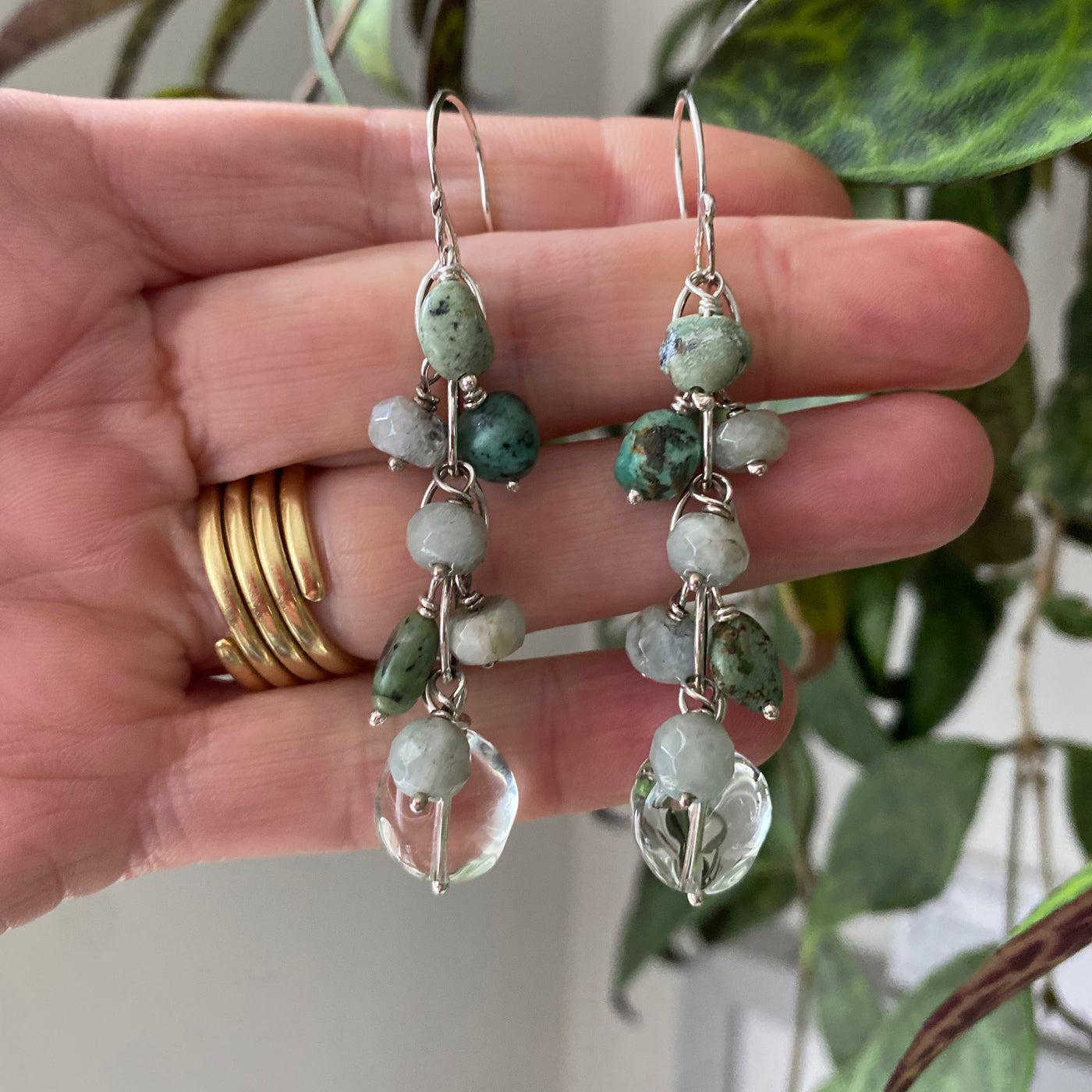 Waterfall style earrings in sterling silver links with pale green prasiolite, dark green blue natural turquoise and sea foam coloured faceted aquamarine gemstones. Held by the hand that made them 
