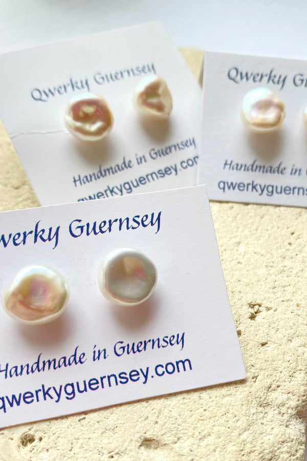 Pearl stud earrings on Qwerky Guernsey branded cards against a textured beige background.