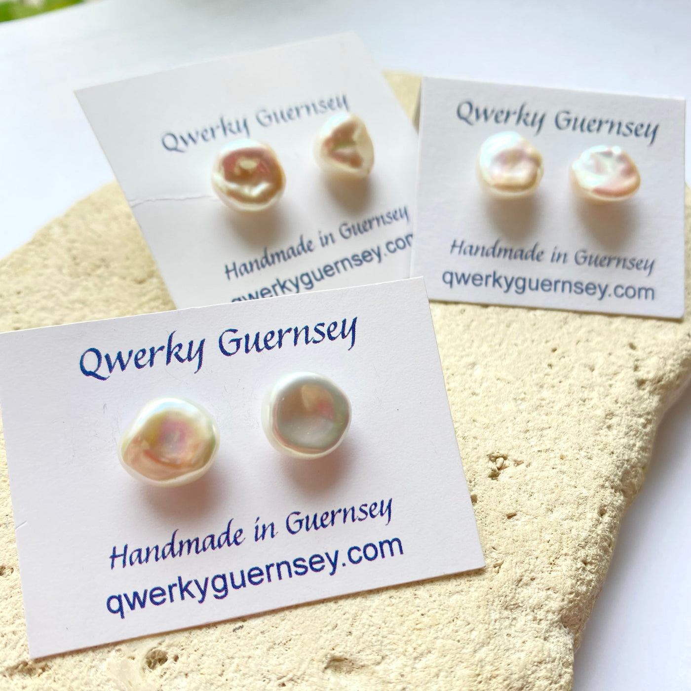 Pearl stud earrings on Qwerky Guernsey branded cards against a textured beige background.