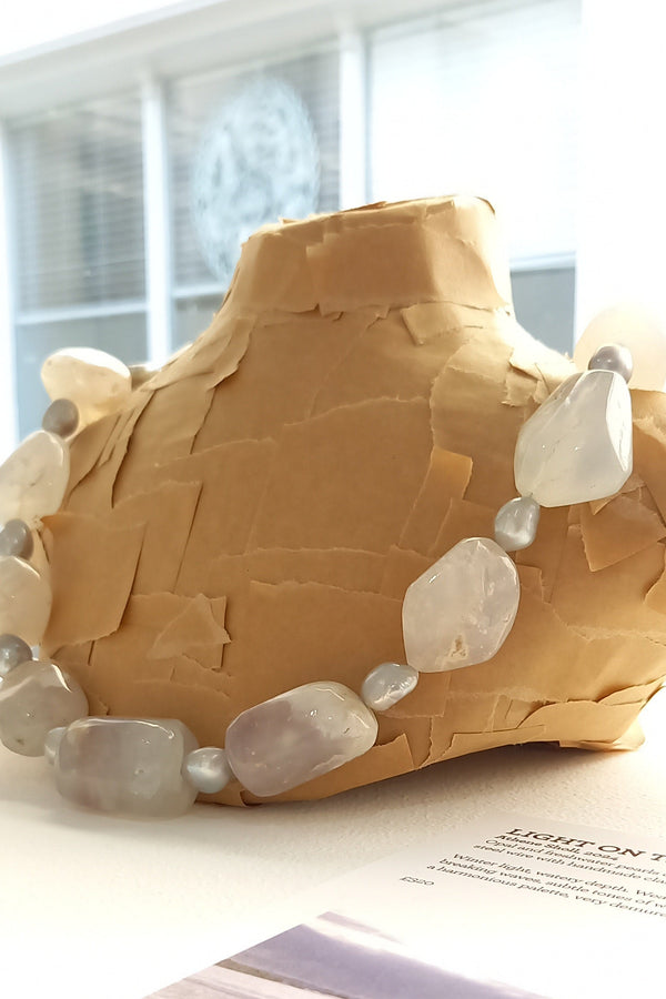 White opal necklace displayed on a bust in a gallery setting. 