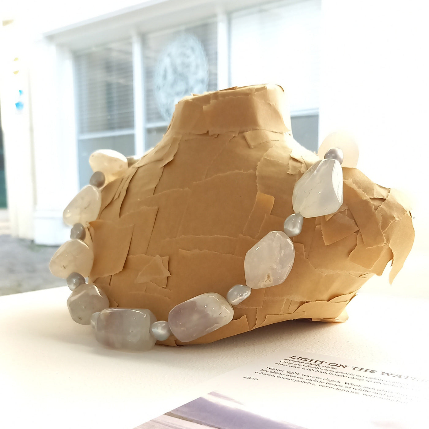 White opal necklace displayed on a bust in a gallery setting. 