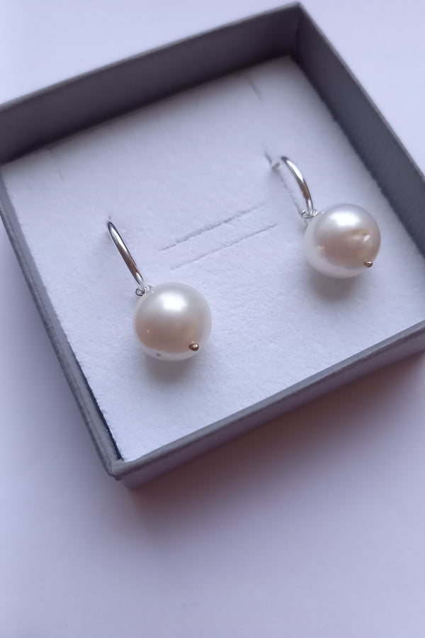 Pearl earrings in a box on a light background