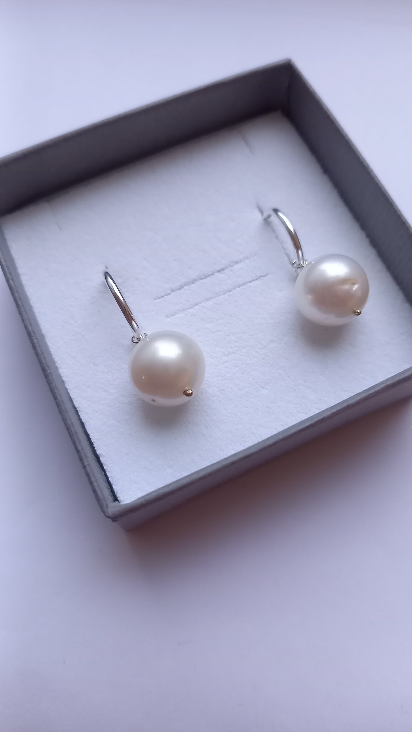 Pearl earrings in a box on a light background