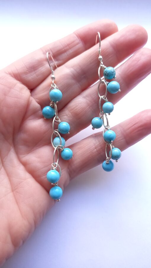 Shoulder grazing turquoise cascading earring dangling over the length of a hand