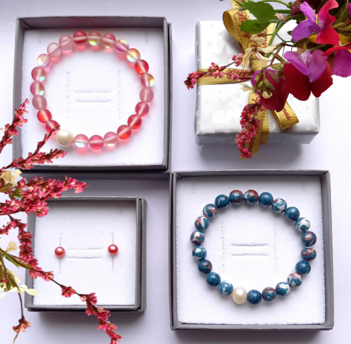 3 open grey gift boxes with pink pearl earrings, pink bracelet and blue bracelet