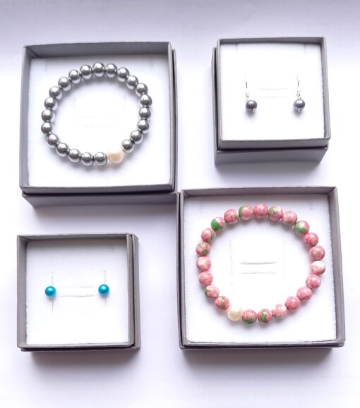Four open gift boxes two containing beaded bracelets and the other a pair of dangle pearl earrings and pearl studs