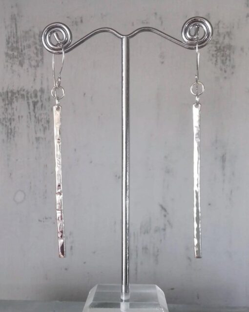 Thin textured silver bars with large handmade hooks hanging on a stand