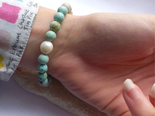 Turquoise Beaded Bracelet with pearl accent in the centre worn on a wrist