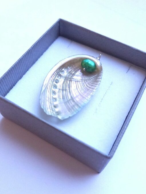 Oval real sea shell pendant with a green pearl attached to the inside of the shell. The shell sits in a grey gift box.