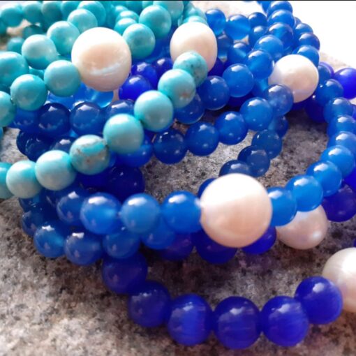 Close up of a stack of blue gemstone beaded bracelets.