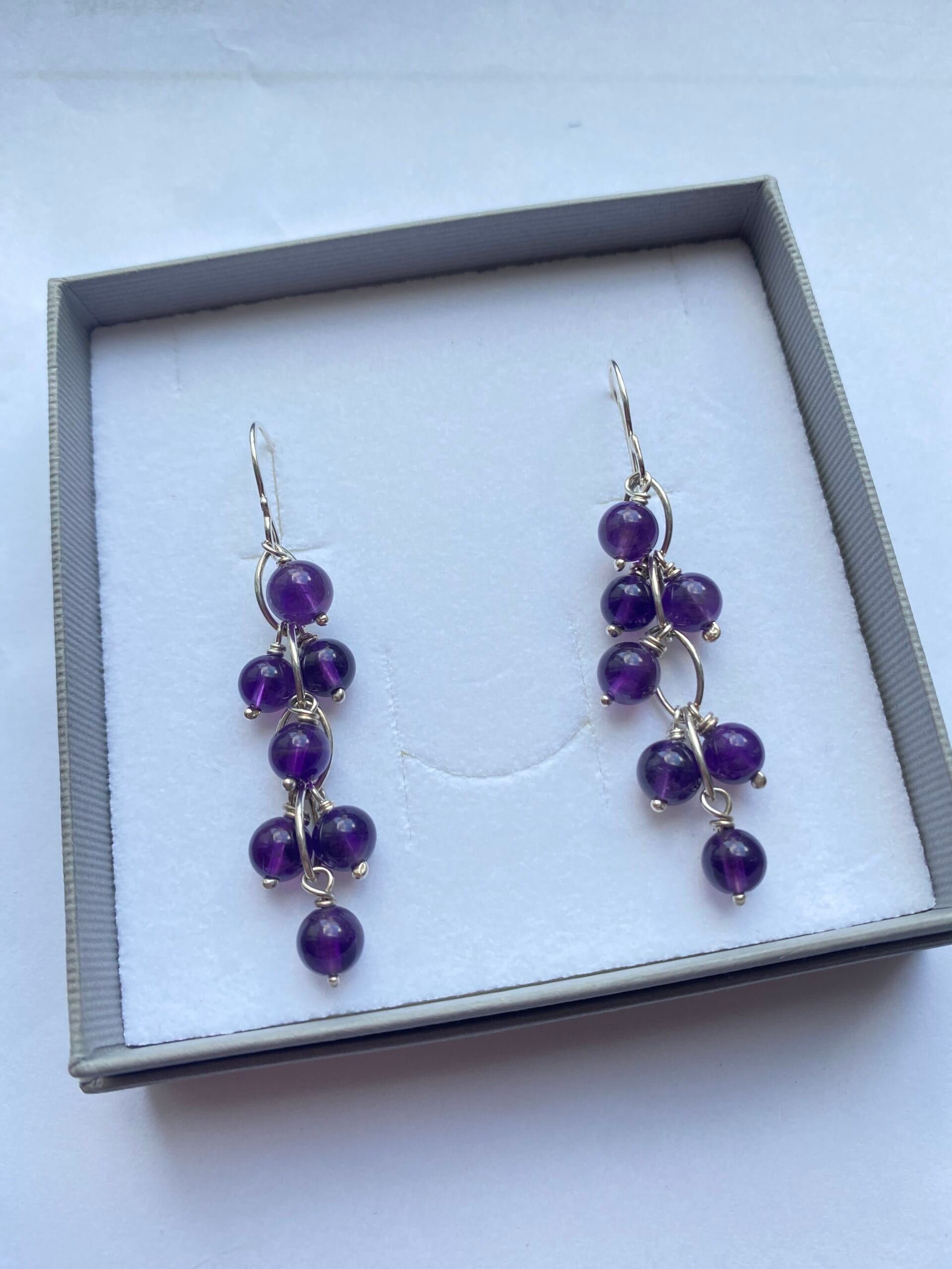 Earrings of amethyst stones suspended from sterling silver links.